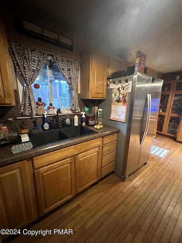 kitchen with light wood finished floors, dark countertops, a sink, and freestanding refrigerator