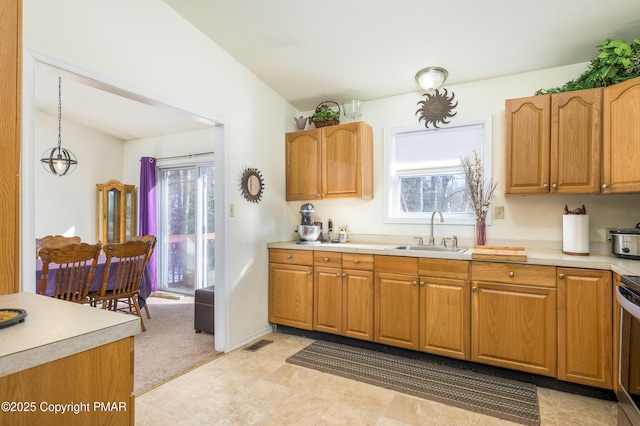 kitchen featuring vaulted ceiling, sink, and hanging light fixtures