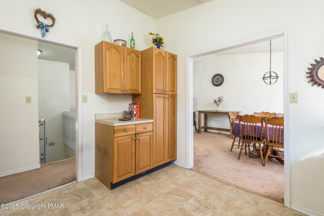 kitchen with light carpet, decorative light fixtures, and radiator heating unit