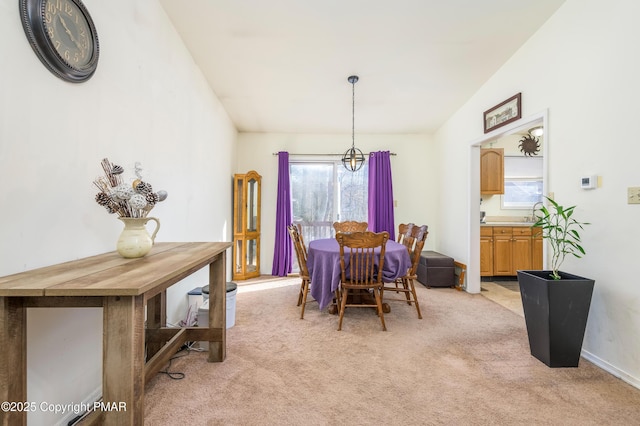 carpeted dining room with lofted ceiling