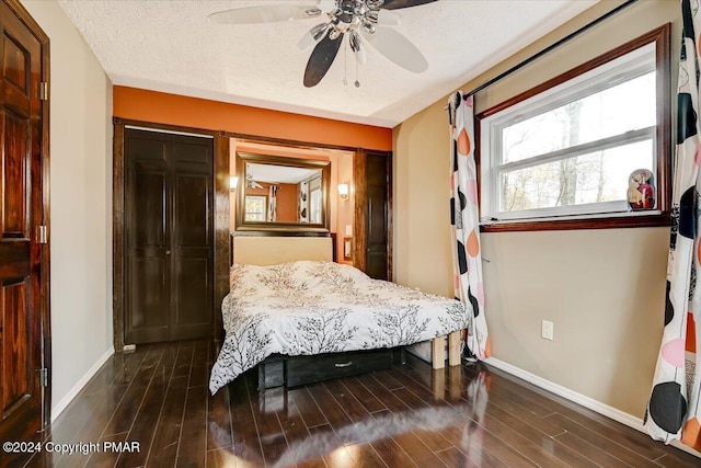 bedroom with a textured ceiling, dark wood finished floors, and baseboards