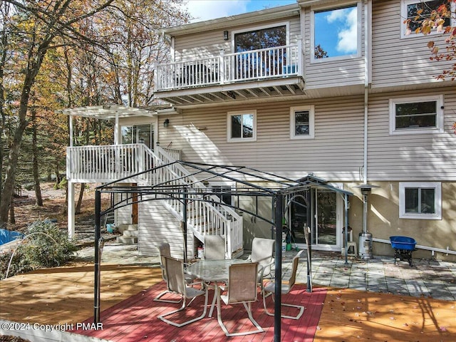 back of property featuring a balcony, stairs, a patio, and outdoor dining space