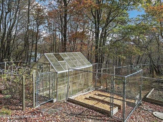 view of greenhouse featuring a garden and fence