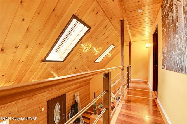 hallway featuring wooden ceiling, a skylight, baseboards, and light wood-style floors