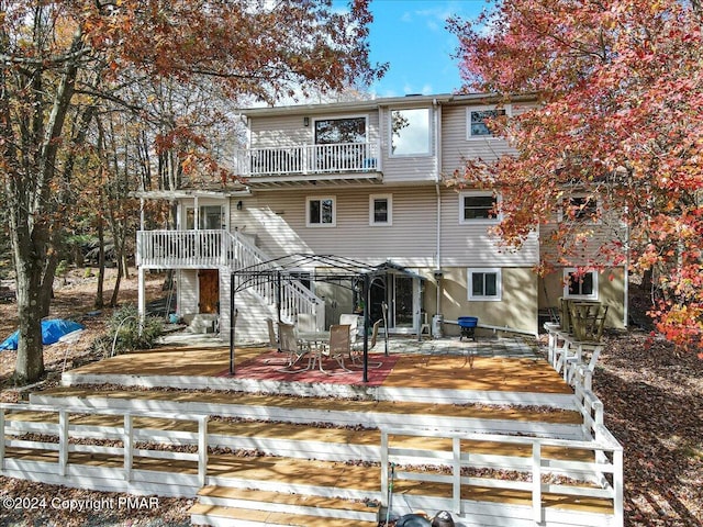 back of property featuring a balcony, a patio area, and stairs