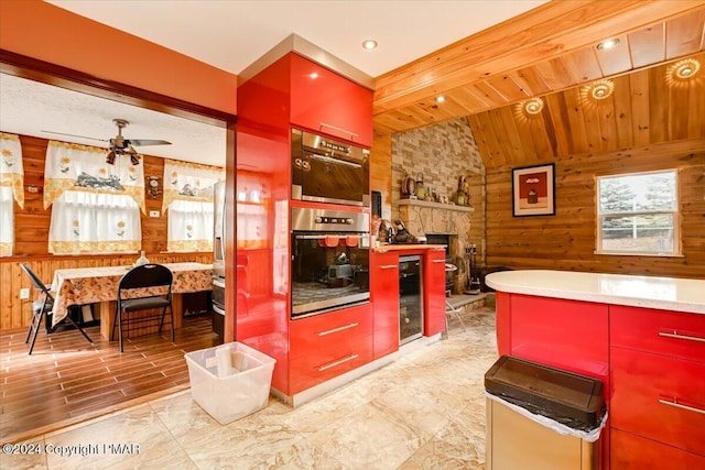 kitchen with wooden walls, red cabinetry, a ceiling fan, wood ceiling, and stainless steel oven