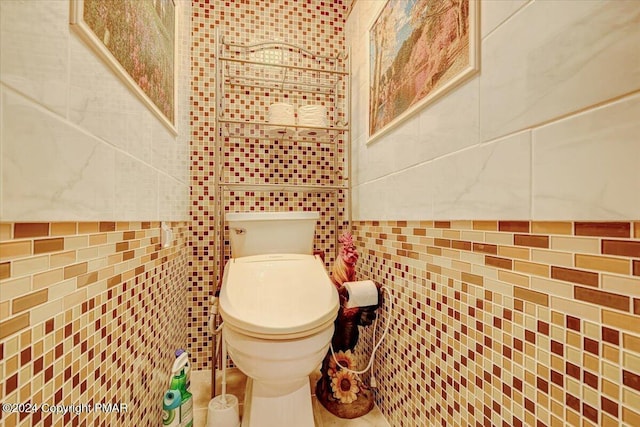 bathroom featuring toilet and tile walls