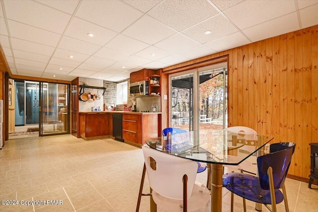 dining space with a paneled ceiling and wood walls