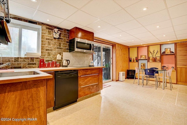 kitchen featuring black dishwasher, light countertops, stainless steel microwave, brown cabinetry, and a sink