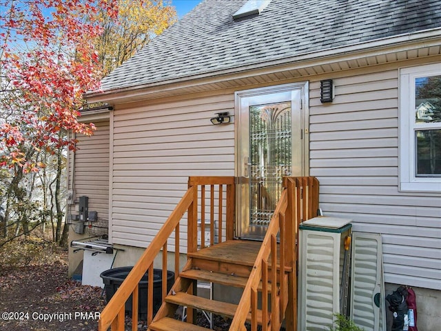 doorway to property featuring roof with shingles