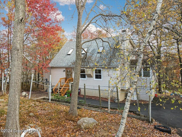 back of house featuring a shingled roof and fence