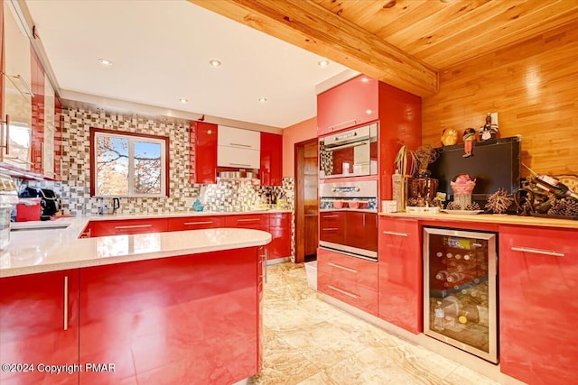 kitchen featuring beverage cooler, double wall oven, a peninsula, backsplash, and beam ceiling