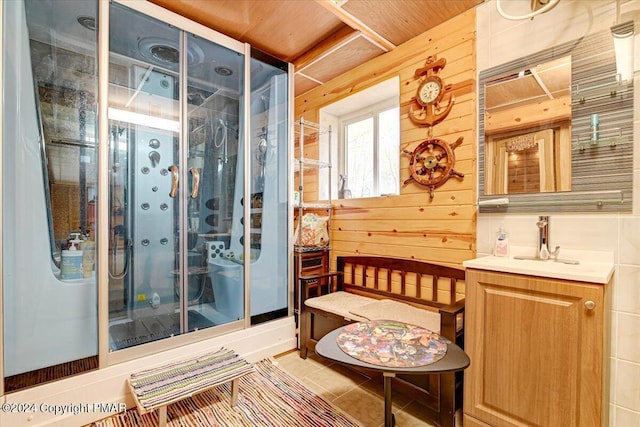 bathroom with wood walls, a stall shower, vanity, and tile patterned floors