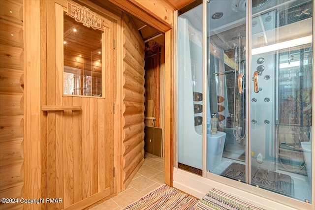 bathroom with rustic walls, a shower stall, and tile patterned floors