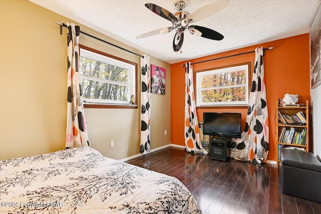 bedroom featuring ceiling fan, a textured ceiling, baseboards, and wood finished floors