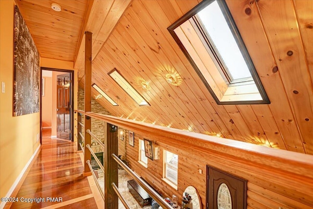 corridor featuring lofted ceiling with skylight, wood ceiling, wood-type flooring, and an upstairs landing