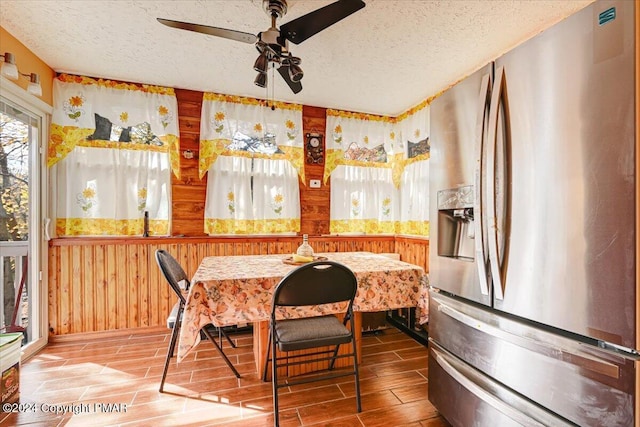 dining room featuring breakfast area, wood finish floors, wood walls, and a textured ceiling