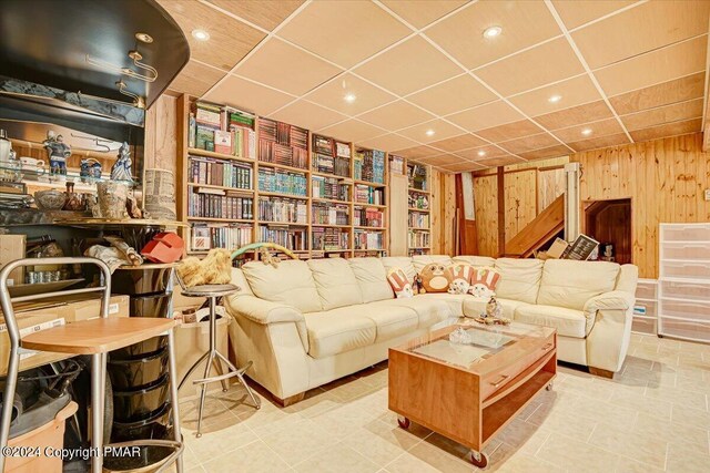 living room with a paneled ceiling, wood walls, recessed lighting, and stairs