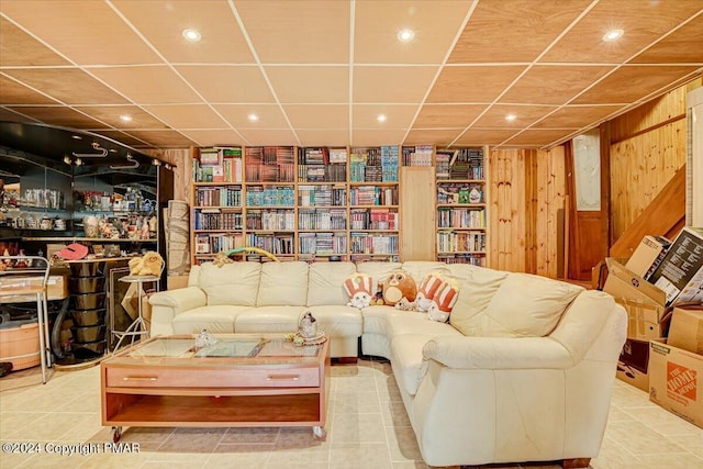 interior space with a drop ceiling, wood walls, and tile patterned floors