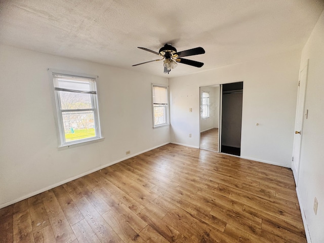 unfurnished bedroom featuring a closet, baseboards, multiple windows, and hardwood / wood-style flooring