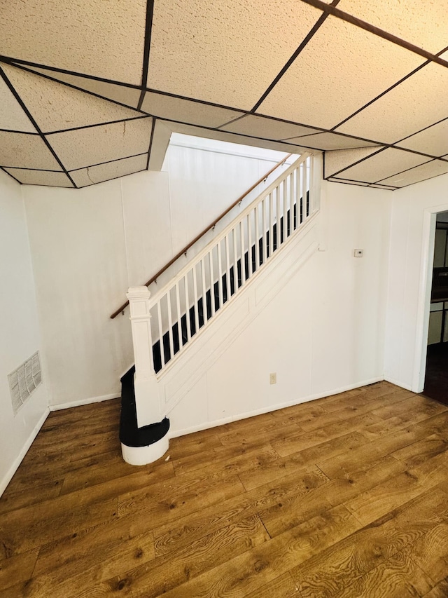 interior space with visible vents, baseboards, a drop ceiling, and wood finished floors