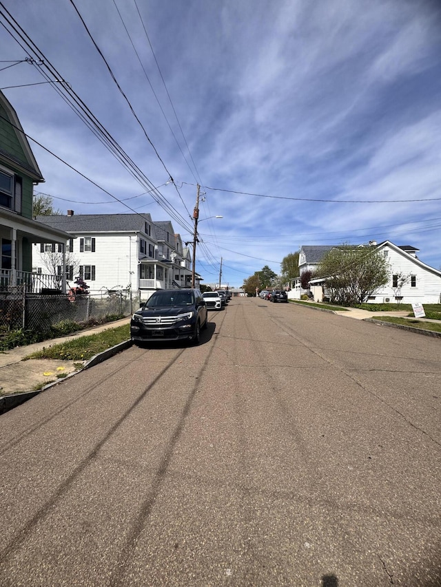 view of street with street lights, a residential view, sidewalks, and curbs