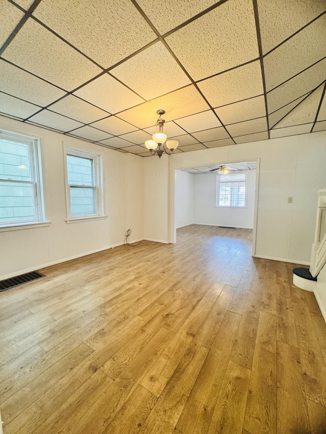 interior space with ceiling fan with notable chandelier, light wood finished floors, a paneled ceiling, and visible vents
