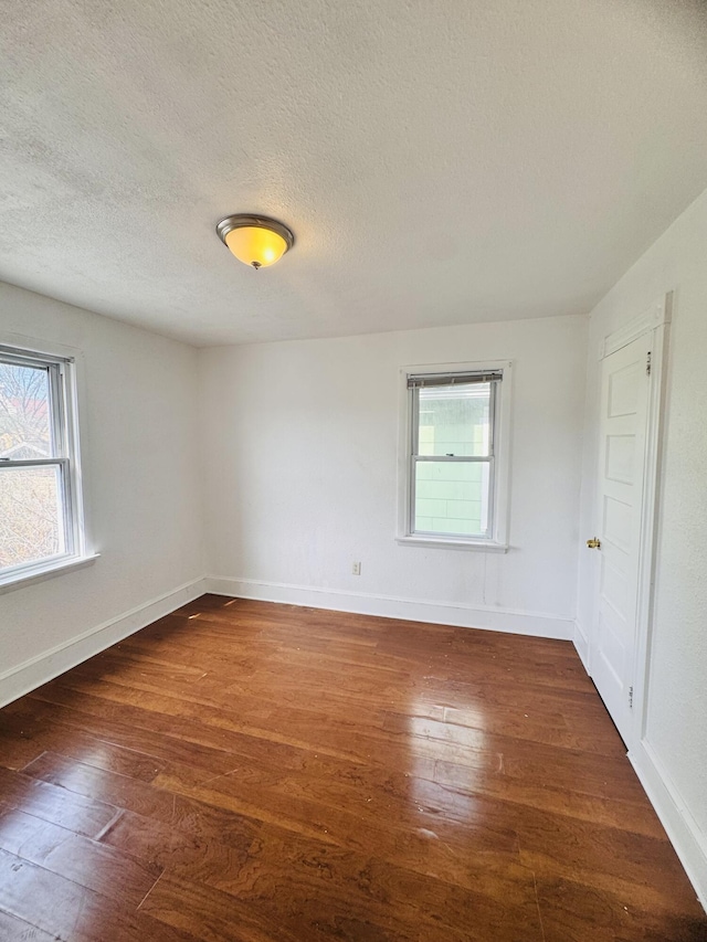 spare room with wood-type flooring, a textured ceiling, and baseboards