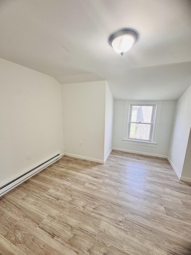 additional living space featuring baseboards, a baseboard radiator, light wood-style flooring, and lofted ceiling