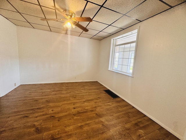 empty room with visible vents, wood finished floors, baseboards, a paneled ceiling, and a ceiling fan