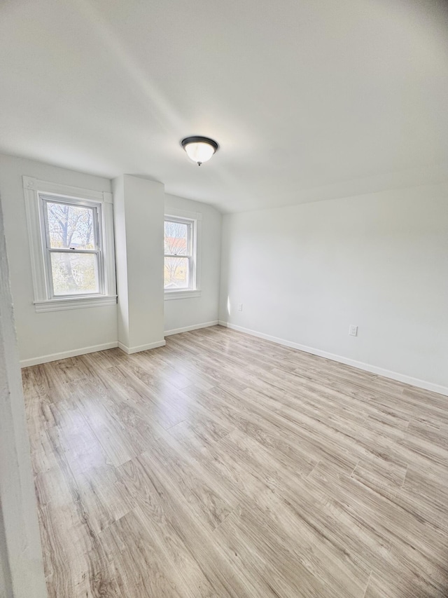 spare room featuring light wood-style floors and baseboards