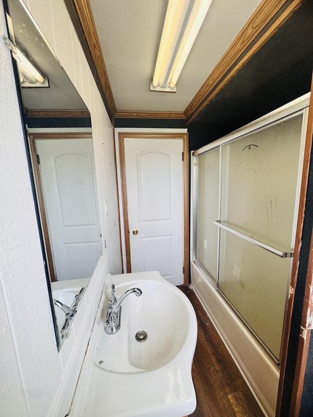 full bath with an enclosed shower, crown molding, a sink, and wood finished floors