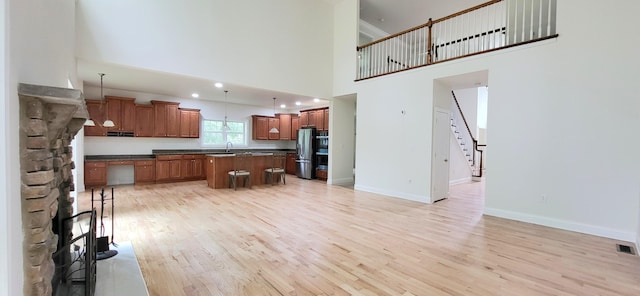 259 Great Bear Way E, Stroudsburg, PA 18302 - kitchen featuring light wood-style flooring, stainless steel refrigerator with ice dispenser, dark countertops, a kitchen island, and a towering ceiling