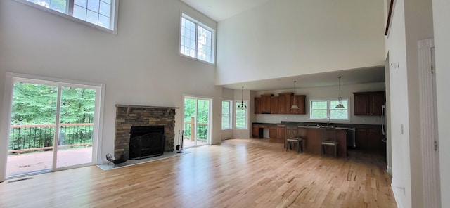 259 Great Bear Way E, Stroudsburg, PA 18302 - unfurnished living room with a towering ceiling, light wood-style flooring, and a stone fireplace