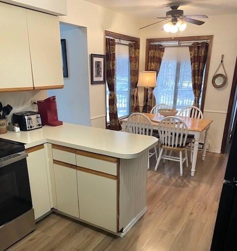 kitchen featuring a peninsula, light wood-type flooring, light countertops, and electric stove