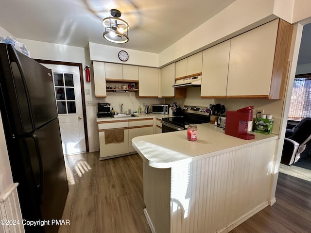 kitchen with dark wood-style floors, stainless steel appliances, a sink, a peninsula, and under cabinet range hood