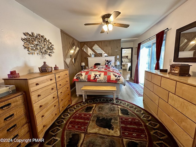 bedroom featuring ceiling fan, wooden walls, and wood finished floors