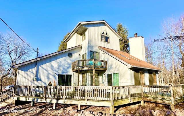 rear view of house with a chimney and a balcony