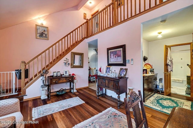 interior space with stairs, baseboards, a high ceiling, and wood finished floors