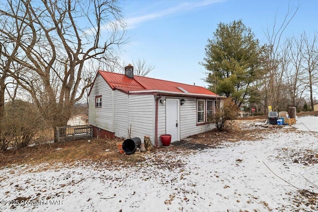 snow covered property with metal roof and a chimney