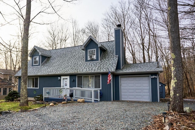 cape cod home featuring a porch, an attached garage, driveway, roof with shingles, and a chimney