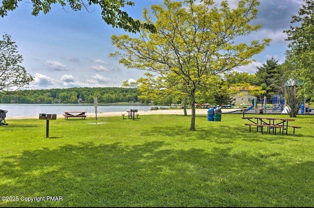 surrounding community featuring playground community, a yard, and a water view