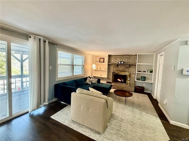 living room featuring dark wood finished floors, built in features, a fireplace, and baseboards