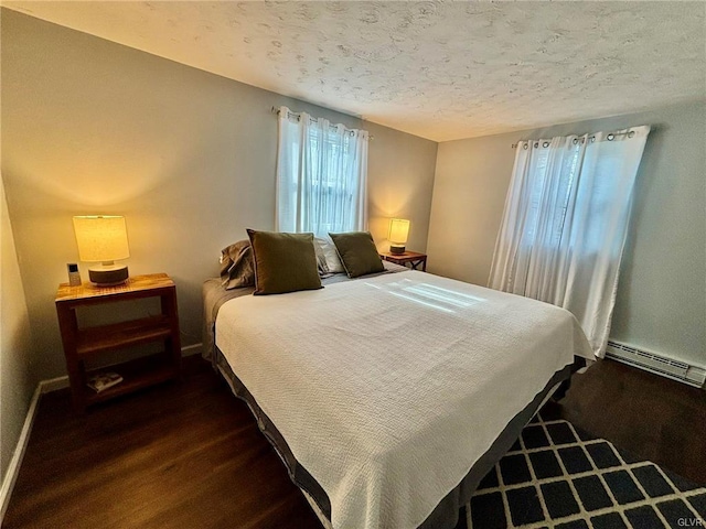 bedroom with a baseboard heating unit, baseboards, dark wood-style flooring, and a textured ceiling