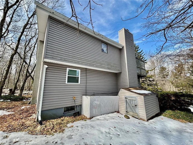 back of property with an outbuilding, a shed, and a chimney