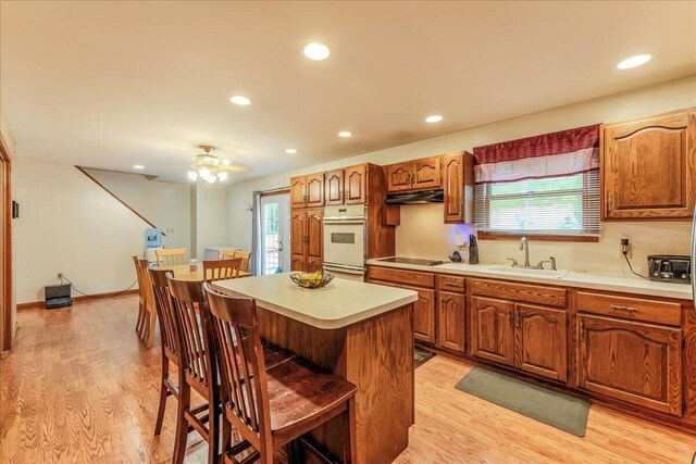 225 Northpark Dr W, East Stroudsburg, PA 18302 - kitchen featuring a sink, white oven, a breakfast bar, light wood-style flooring, and healthy amount of natural light