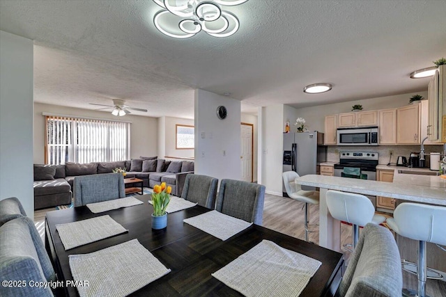 dining area with a textured ceiling, ceiling fan, and wood finished floors