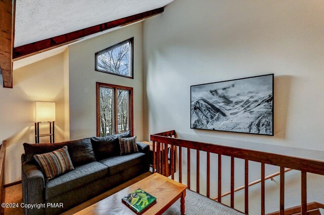 carpeted living area featuring beamed ceiling, high vaulted ceiling, and a textured ceiling