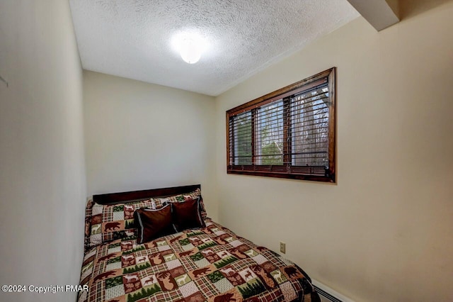 bedroom with baseboard heating and a textured ceiling