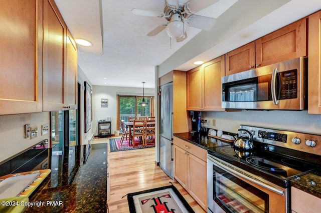 kitchen with a ceiling fan, dark stone countertops, light wood-style floors, and appliances with stainless steel finishes